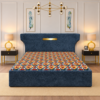 Zane Diwan Cum Bed with navy-blue upholstered frame, gold headboard accent, and colorful geometric bedding