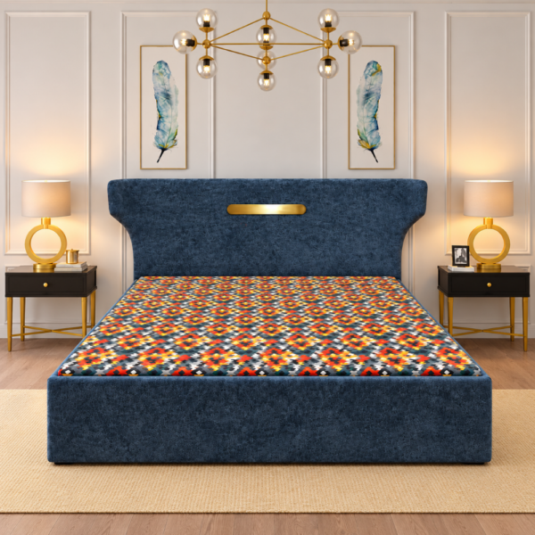 Zane Diwan Cum Bed with navy-blue upholstered frame, gold headboard accent, and colorful geometric bedding
